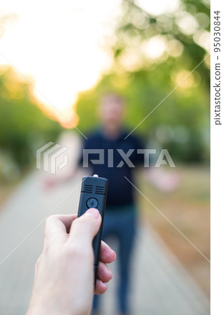A stun gun in a woman's hand, protection from an attacking man A stun gun in a woman's hand, protection from an attacking man 95030844