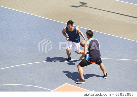young asian male basketball players playing a game on outdoor court 95032095
