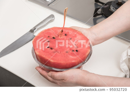 [A middle-aged housewife makes cut watermelons, turning them over and transferring them to a bowl] 95032720