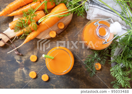 Healthy food concept, fresh natural juice. Glass jar of fresh carrot juice with fresh carrots on a rustic table. View from above. Healthy food concept, fresh natural juice. Glass jar of fresh carrot juice with fresh carrots on a rustic table. View from above. 95033488