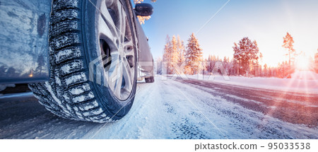 Closeup view of the car's wheel on the snowy road in natural park 95033538