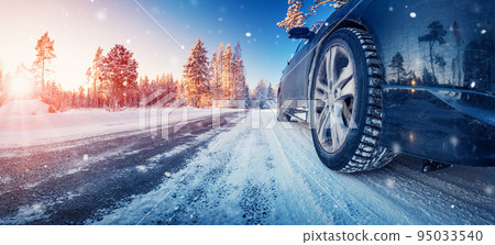 Closeup view of the car's wheel on the snowy road in natural park 95033540