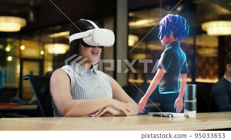 Asian woman wearing VR headset communicates with cartoon character via hologram 95033653