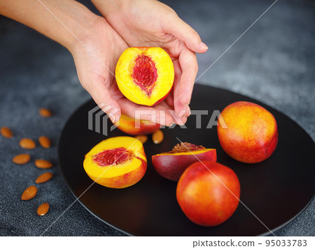Hand holding fresh peach fruit and black dish Hand holding fresh peach fruit and black dish 95033783
