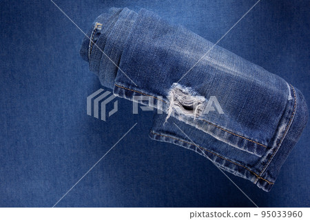 Folded blue jeans denim background texture. Jeans fabric material surface 95033960