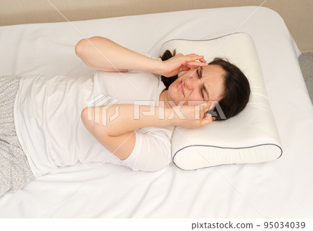 The woman woke up with a headache, a morning migraine or an improperly selected pillow. The woman woke up with a headache, a morning migraine or an improperly selected pillow. 95034039