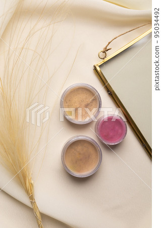 Cosmetics facial powder and blush for cheeks on natural background with dried flowers. Makeup accessories top view 95034492