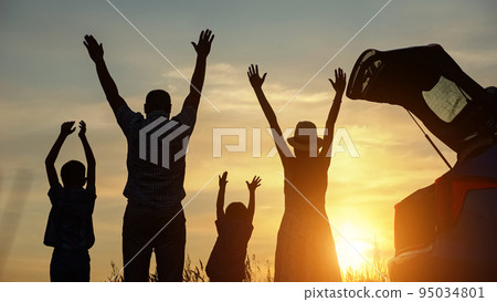 Parents and kids raising hands to sky enjoy summer sunset 95034801