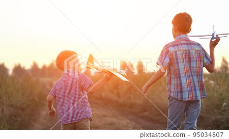Boy siblings run past fields to launch airplanes to sky Boy siblings run past fields to launch airplanes to sky 95034807