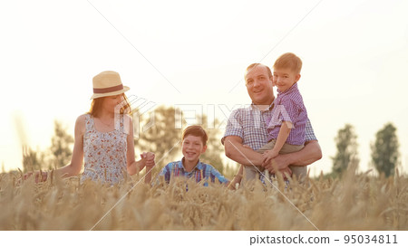 Happy family enjoys spending summer holidays on wheat field Happy family enjoys spending summer holidays on wheat field 95034811