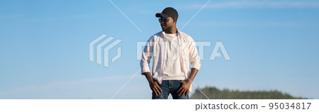 African American man in a cap and sunglasses stands on the street African American man in a cap and sunglasses stands on the street 95034817