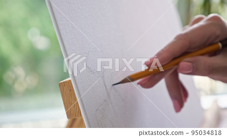 Person hands draw flowers using pensil on easel closeup 95034818