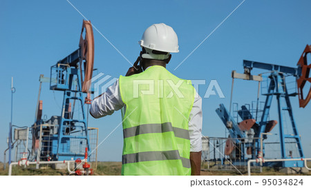 African American man talks on phone on jack-pump operation 95034824