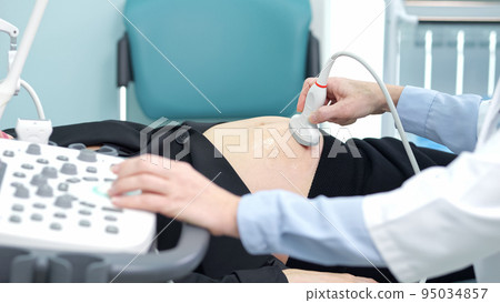 Doctor holds ultrasonic probe determining baby gender Doctor holds ultrasonic probe determining baby gender 95034857