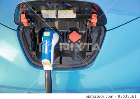 Electric car charging in parking lot 95035161