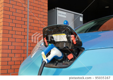 Electric car charging in parking lot 95035167