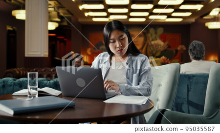 Businesswoman working on laptop in restaurant Businesswoman working on laptop in restaurant 95035587