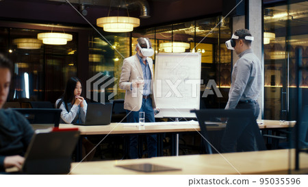 Engineers examining blueprint in VR headsets Engineers examining blueprint in VR headsets 95035596