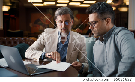 Mature man showing contract to businessman 95035658