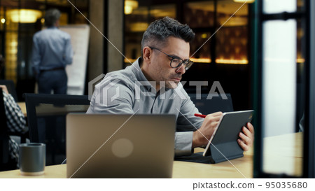 Man working in office on digital tablet Man working in office on digital tablet 95035680
