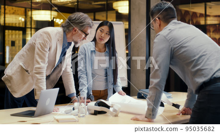 Team of engineers discussing blueprint in office room Team of engineers discussing blueprint in office room 95035682