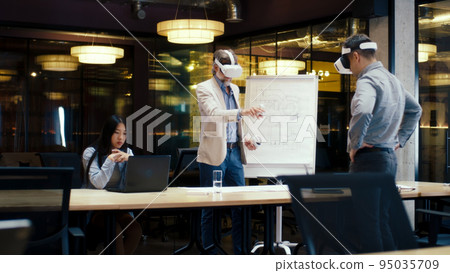 Engineers examining blueprint in VR headsets Engineers examining blueprint in VR headsets 95035709
