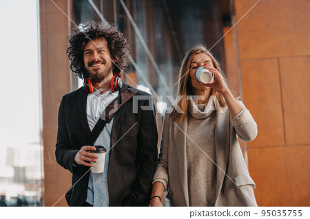 Business man and business woman talking and holding luggage traveling on a business trip, carrying fresh coffee in their hands.Business concept 95035755