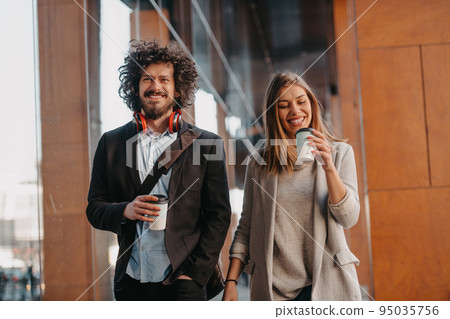 Business man and business woman talking and holding luggage traveling on a business trip, carrying fresh coffee in their hands.Business concept 95035756