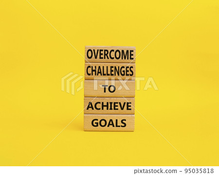 Challenges or goals symbol. Wooden blocks with words 'Overcome challenges to achieve goals'. Beautiful yellow background. Business and 'Overcome challenges to achieve goals' concept. Copy space. 95035818
