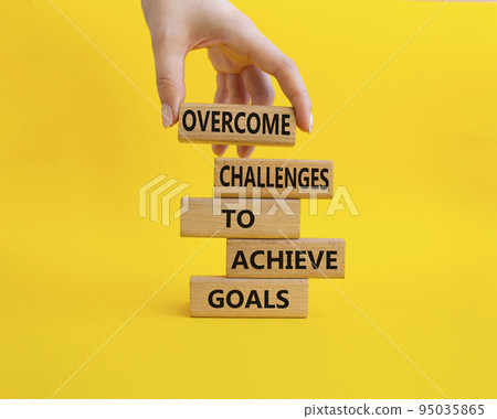 Challenges or goals symbol. Wooden blocks with words Overcome challenges to achieve goals. Beautiful yellow background. Businessman hand. Overcome challenges to achieve goals concept. Copy space 95035865