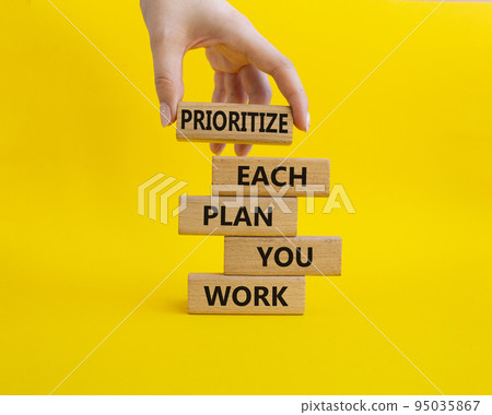 Priority, plan and work symbol. Wooden blocks with words Prioritize each plan you work. Beautiful yellow background. Businessman hand. Business and Prioritize each plan you work concept. Copy space Priority, plan and work symbol. Wooden blocks with words Prioritize each plan you work. Beautiful yellow background. Businessman hand. Business and Prioritize each plan you work concept. Copy space 95035867