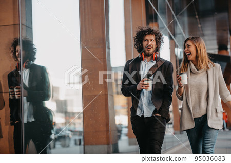 Business man and business woman talking and holding luggage traveling on a business trip, carrying fresh coffee in their hands.Business concept 95036083