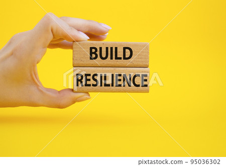 Build resilience symbol. Wooden blocks with words Build resilience. Beautiful yellow background. Businessman hand. Business and Build resilience concept. Copy space. 95036302