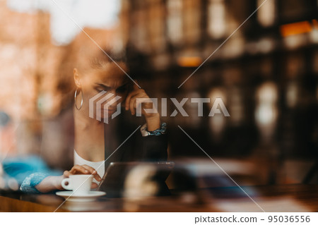 woman in a coffee shop drink coffee viewed through glass with reflections as they sit at a table chatting and laughing woman in a coffee shop drink coffee viewed through glass with reflections as they sit at a table chatting and laughing 95036556