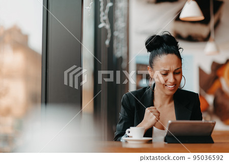 A woman sits in a cafe with her arms raised and celebrating a job well done.Business concept 95036592