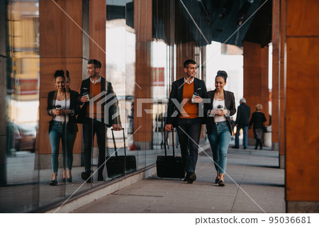 Business man and business woman talking and holding luggage traveling on a business trip, carrying fresh coffee in their hands.Business concept Business man and business woman talking and holding luggage traveling on a business trip, carrying fresh coffee in their hands.Business concept 95036681