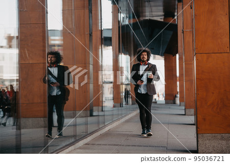 Trendy businessman with leather briefcase in financial district using smartphone while listening audio songs headphones drinking coffee Trendy businessman with leather briefcase in financial district using smartphone while listening audio songs headphones drinking coffee 95036721
