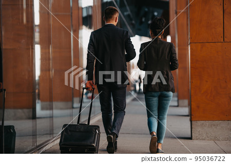 Business man and business woman talking and holding luggage traveling on a business trip, carrying fresh coffee in their hands.Business concept 95036722