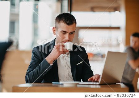 Happy business man sitting at cafeteria with laptop and smartphone Happy business man sitting at cafeteria with laptop and smartphone 95036724