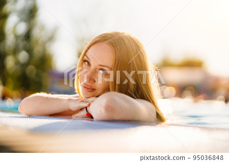 A portrait of beautiful woman by the side of a pool. A portrait of beautiful woman by the side of a pool. 95036848