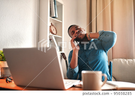 Tired business man with neck pain on a laptop and phone call, looking stressed and stretching bad, strained muscle or sore back. Stressed, multitasking guy having a difficult time working from home 95038285