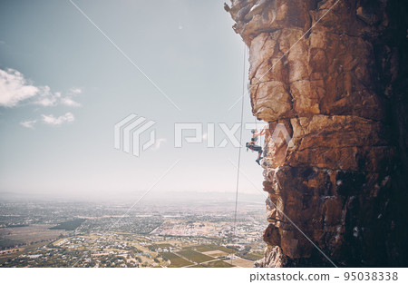 Mountain, rock climbing and sport with a sports woman and climber abseiling on a mountainside outdoor in nature. Fitness, exercise and training with a female athele using a rop to climb a cliff 95038338