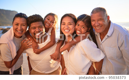 Portrait of happy family with children smile and hug together on a sunset beach. Adorable little kids bonding with mother, father, grandmother and grandfather outdoor on summer vacation at the ocean 95038373
