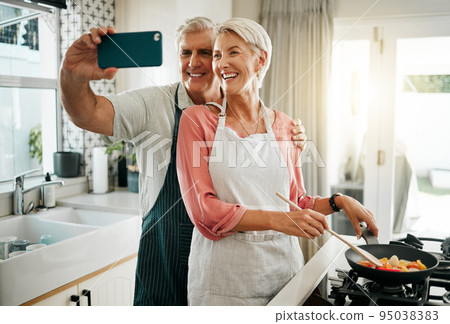 Old couple, phone selfie and cooking in kitchen, delicious meal and food in home. Love, smile and happy elderly retired romantic man and woman cook breakfast in the morning and take picture together. 95038383