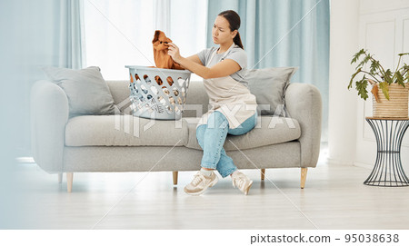 Asian woman, laundry or clothes basket on sofa in house living room and looking confused at dirty stains. Stress, anxiety or worry of person with washing clothing or cleaning fabric in home interior 95038638