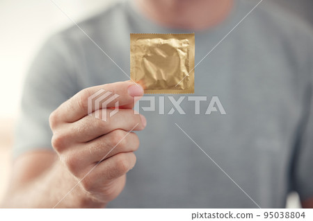 Condom in man hand for safe sex, sexual safety and hiv awareness zoom. Person with male contraceptive product for sexual risk prevention, healthcare and caution for security, trust and love choice Condom in man hand for safe sex, sexual safety and hiv awareness zoom. Person with male contraceptive product for sexual risk prevention, healthcare and caution for security, trust and love choice 95038804