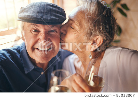 Love, toast and old couple kiss with champagne in celebration of a happy marriage anniversary together at home. Smile, romance and senior woman enjoying a relaxing wine date and drink elderly partner Love, toast and old couple kiss with champagne in celebration of a happy marriage anniversary together at home. Smile, romance and senior woman enjoying a relaxing wine date and drink elderly partner 95038807