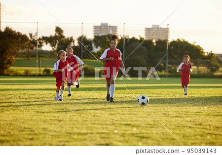 Sports, fitness and soccer training by girl team playing on grass field, teamwork during football game. Health, exercise and children learning to play in competitive match with energy and soccer ball Sports, fitness and soccer training by girl team playing on grass field, teamwork during football game. Health, exercise and children learning to play in competitive match with energy and soccer ball 95039143