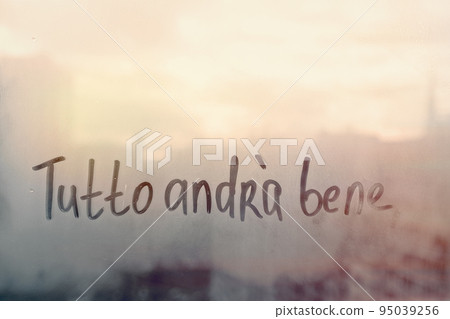 Lettering Italian text Tutto andra bene everything will be fine in english on sunset wet window 95039256