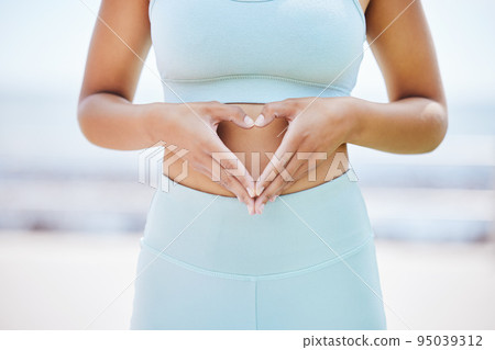 Fitness, health and heart with hands of woman on stomach for wellness, sports and goals. Workout, hope and sports with girl holding love sign against abdomen for exercise, motivation and vision 95039312